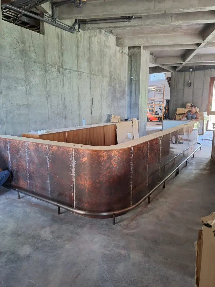 Just found a large wooden box in an abandoned warehouse. It's bigger than I expected!0 A sturdy wooden bar with a shiny copper finish, standing tall in a rustic building.